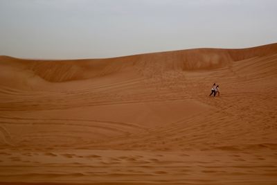 View of people on sand dunes in desert against sky