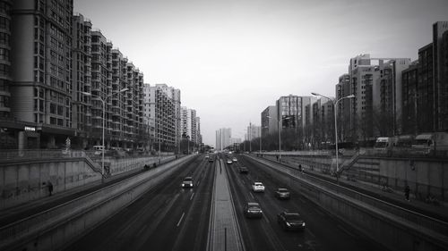 Vehicles on road in city against sky