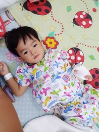 High angle portrait of cute baby girl with medical equipment lying on bed at home