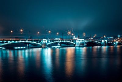 Illuminated harbor by sea against sky at night