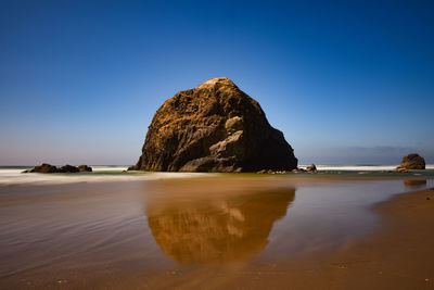 Rock formation on beach against clear blue sky