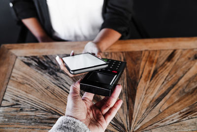 Close up of woman doing contact less payment with mobile phone in cafe. technology and shopping