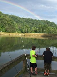 Rear view of boys fishing at lake