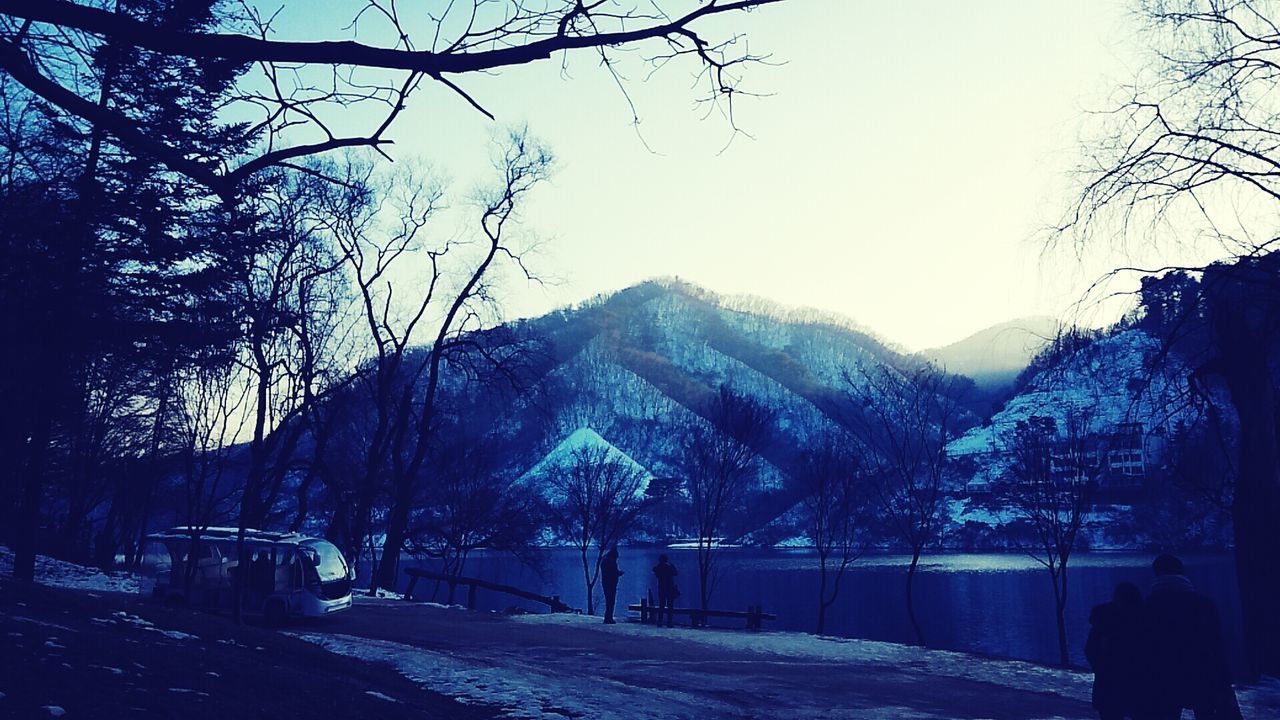 mountain, tree, clear sky, winter, building exterior, bare tree, season, snow, built structure, cold temperature, sky, nature, architecture, lifestyles, men, leisure activity, road, mountain range, day