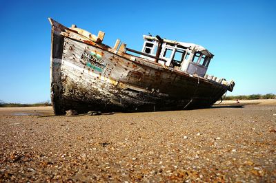 Abandoned ship on beach against clear sky