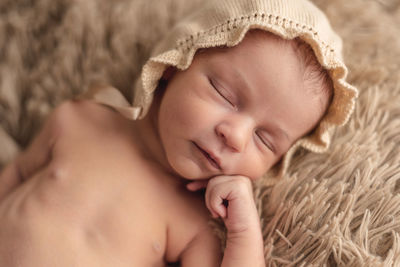 A newborn baby sleeping peacefully in a brown hat. newborn session concept