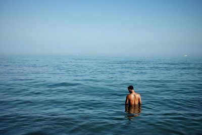 Rear view of man looking at sea against sky