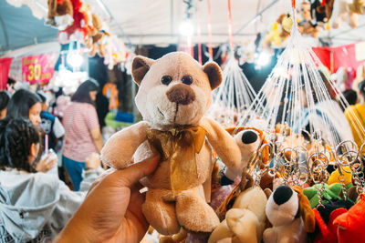 Cropped hand holding teddy bear at market