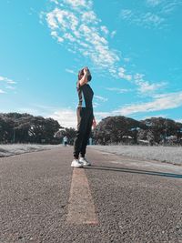 Side view of woman standing on road against sky