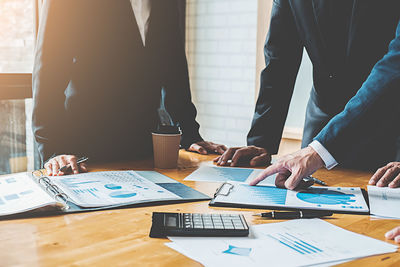 Cropped image of business people working on graph at desk in office