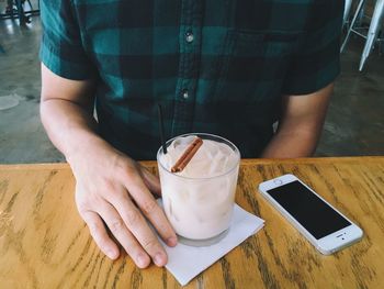 Midsection of man holding smart phone on table