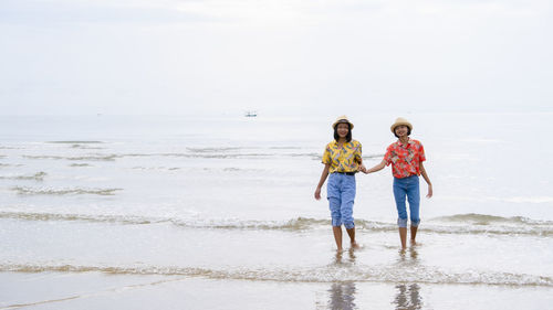 Full length of friends on beach against sky