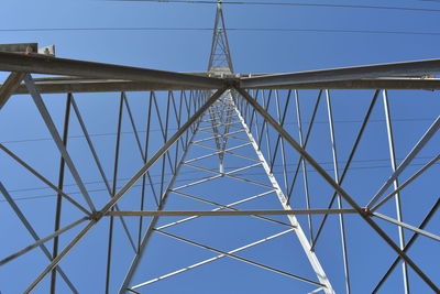 Low angle view of electricity pylon against blue sky