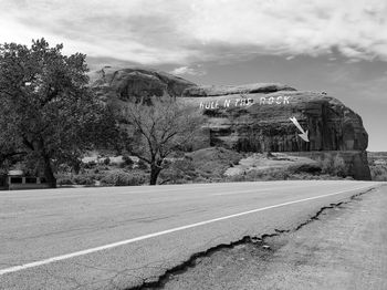 Road by trees against sky in city