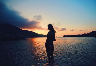 Silhouette man on lake against sky during sunset