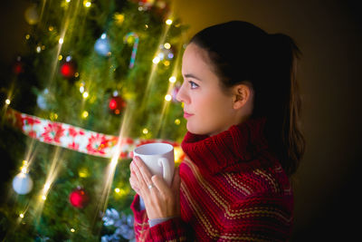 Woman holding illuminated christmas tree in park during winter