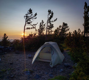 Tent on field against sky at sunset