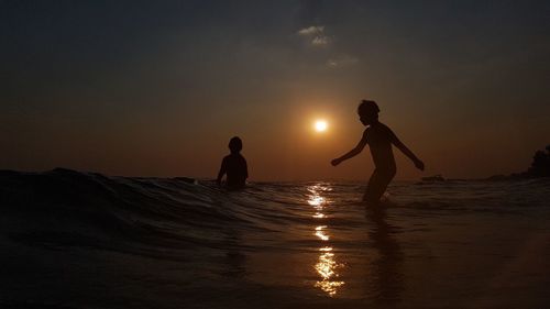 Silhouette men on beach against sky