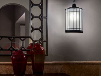 Close-up of illuminated lamp on table against wall at home