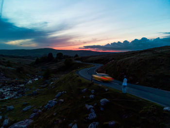 Cars on road against sky at sunset