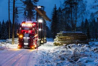 Loading logs on lorry at dusk