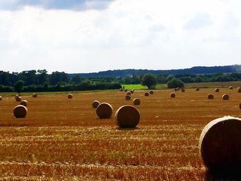 Hay bales on field against sky