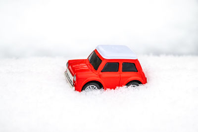 Red toy car on snow covered field