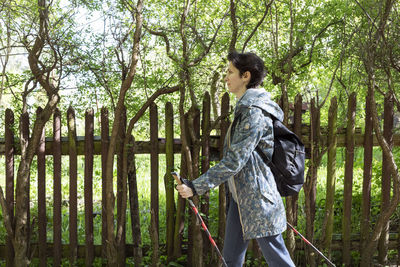 Nordic walking. caucasian woman walks with trekking poles and backpack, physical activity in