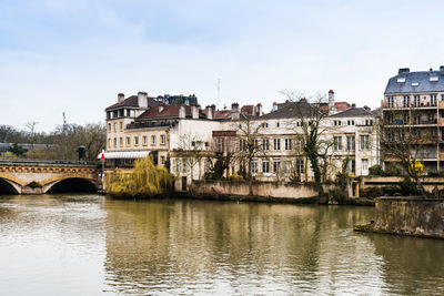 Bridge over river by buildings against sky