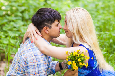 Young couple kissing against plants