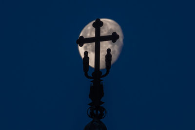 Low angle view of silhouette cross against clear blue sky