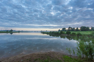 Scenic view of calm lake against cloudy sky