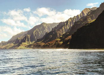 Scenic view of sea by mountains against sky 