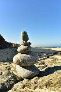 Stack of pebbles on beach against clear blue sky