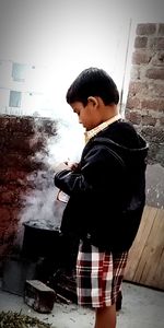 Side view of young man standing against wall