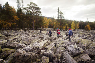 Hikers walking on rocks against sky