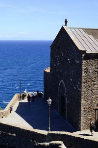 People by sea against church. italy, sardinia