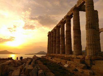 View of old ruins by sea against sky during sunset
