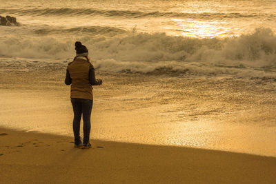 Rear view of woman standing on beach