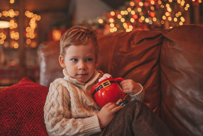 Portrait candid happy kid in knit beige sweater hold xmas mug with marshmallows and candy cane