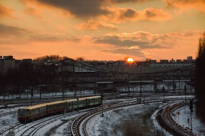 Train on tracks against sky during sunset