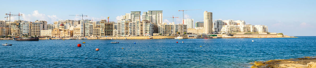 Sailboats in sea against buildings in city