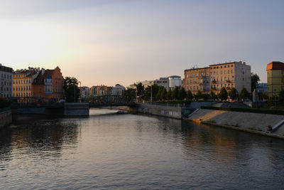 Buildings by river against clear sky