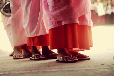 Low section of women wearing pink saris while standing on field