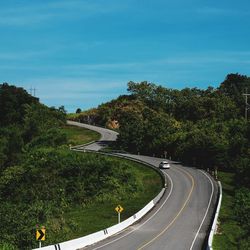 Road amidst plants and trees against sky