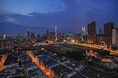 Illuminated modern buildings in city against sky at night