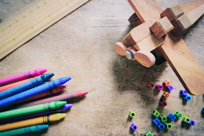 High angle view of multi colored crayons with model airplane on table