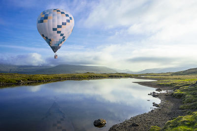 Hot air balloon flying over water against sky