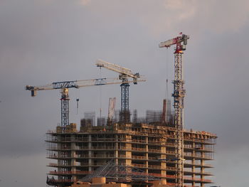 Cranes at construction site against sky