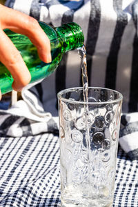 Close-up of hand pouring water in glass on table